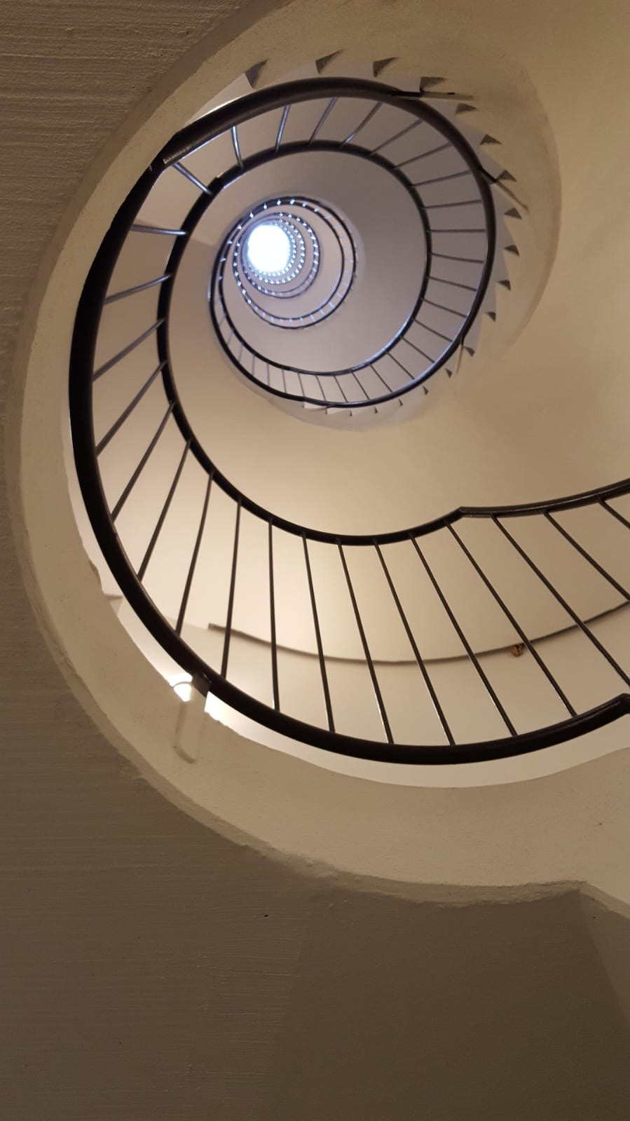 Escada em espiral vista de baixo, com luz entrando no topo